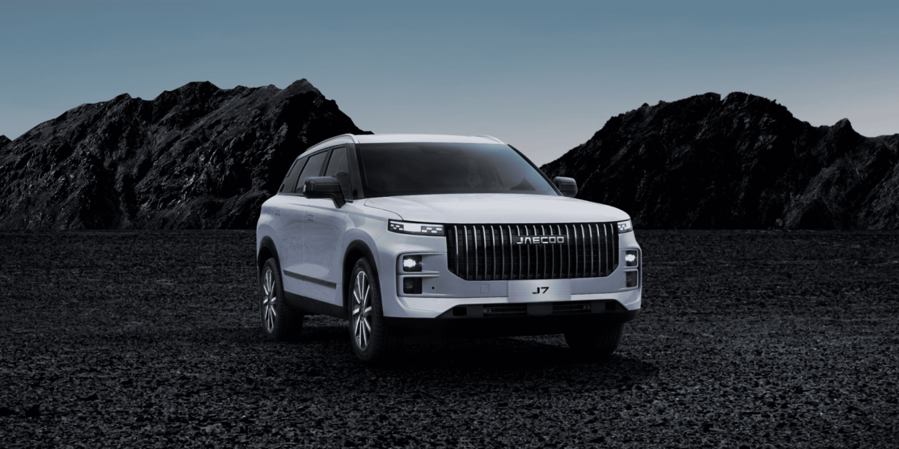 White Jaecoo J7 SUV on rocky terrain with mountains in the background.